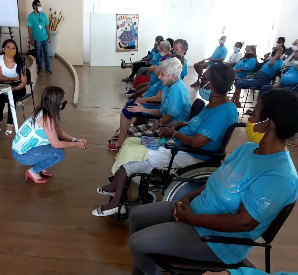 Participantes sentados em roda durante atividade do EnvelheSer em ambiente interno
