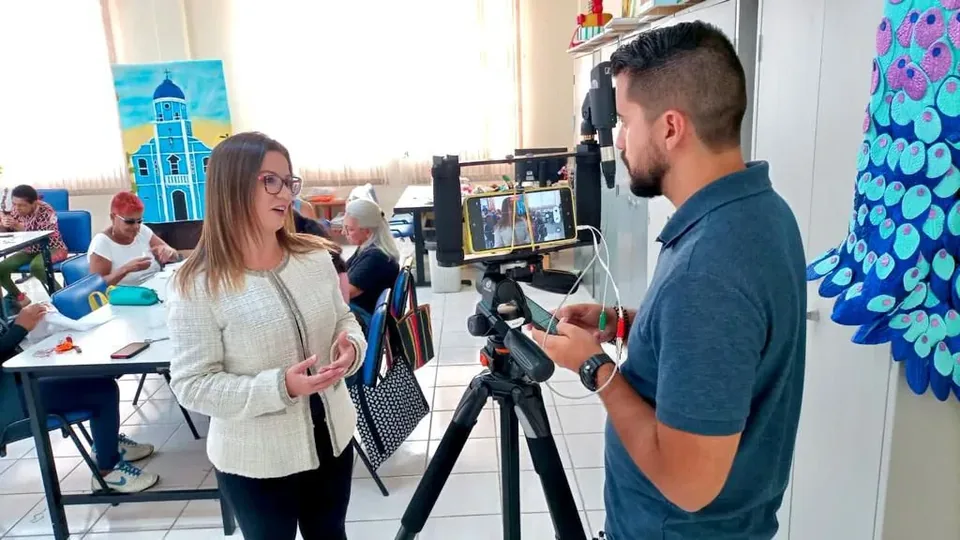 Vanessa Fortes falando diante de uma câmera durante gravação em ambiente interno