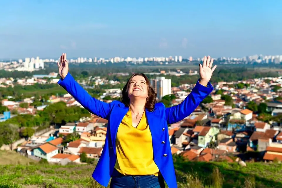 Vanessa Fortes de braços abertos diante de uma vista urbana